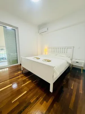 a white bedroom with a large bed and a window at \u96c5\u5178\u5357\u90e8\u6d77\u6ee82km\u7684\u8212\u9002\u5bbd\u655e\u516c\u5bd3 in Athens