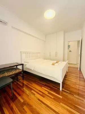 a bedroom with a large white bed and a wooden floor at \u96c5\u5178\u5357\u90e8\u6d77\u6ee82km\u7684\u8212\u9002\u5bbd\u655e\u516c\u5bd3 in Athens