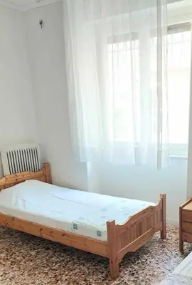 a wooden bed in a room with a window at Room for 2 in a dormitory 5' from metro in Athens