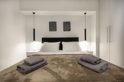 a bedroom with a large bed with two towels on it at Black & White 2BR Apt steps from Mavili Square in Athens