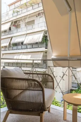a rattan chair and a table on a balcony at Ilisia Urban Elegance in Athens
