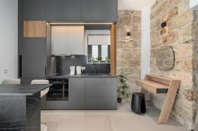 a kitchen with black cabinets and a stone wall at 'Green & Blue' Castella Luxury Suites in Piraeus