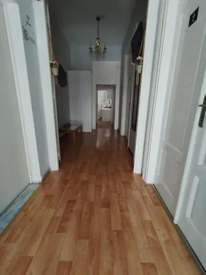 an empty hallway with a wooden floor and a chandelier at Apartment Atiki metro shared bathroom and kitchen in Athens