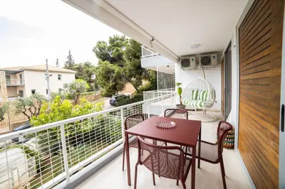 a balcony with a table and chairs and a view of a street at 12LVE Vouliagmeni Apartment in Athens