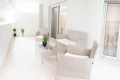 a white living room with a chair and a table at Sweet Family Home 2 in Athens