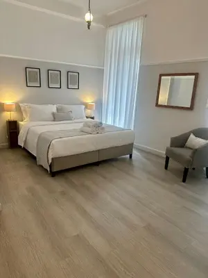a white bedroom with a large bed and a chair at elan RESIDENCE in Athens