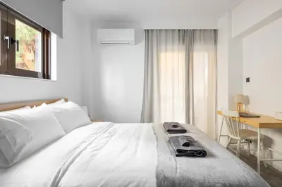 a bedroom with a large white bed with a desk and a desk at Modern Two-Bedroom Haven near Paleo Faliro Beach in Athens