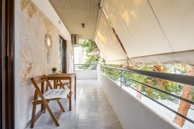a room with a table and a chair on a balcony at Modern Two-Bedroom Haven near Paleo Faliro Beach in Athens
