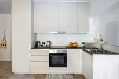 a white kitchen with white cabinets and a sink at Modern Two-Bedroom Haven near Paleo Faliro Beach in Athens