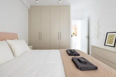 a white bedroom with a bed with two towels on it at Modern Two-Bedroom Haven near Paleo Faliro Beach in Athens