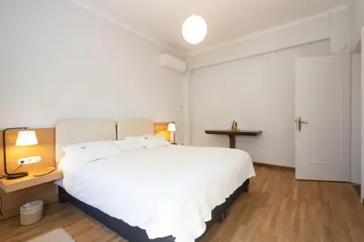 a bedroom with a large white bed and a table at Unbeatable Acropolis Elegant 2-Bedroom Apartment on Areopagitou in Athens