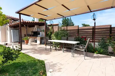 a patio with a table and chairs under an umbrella at Artemis Riviera Near Athen's Airport By SEM in Artemida