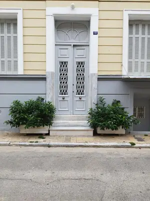 a white door on a house with two plants at Apartment Atiki metro shared bathroom and kitchen in Athens