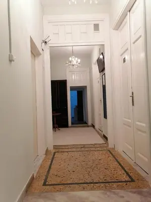 a hallway with white walls and a chandelier at Apartment Atiki metro shared bathroom and kitchen in Athens