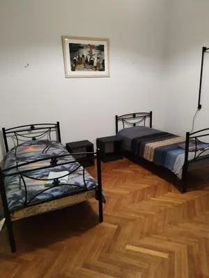 two beds in a room with a wooden floor at Apartment Atiki metro shared bathroom and kitchen in Athens