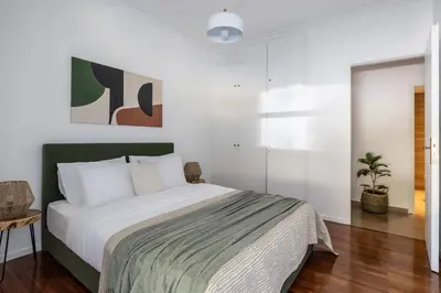 a bedroom with a large bed with white walls at Stylish 1BR Retreat Near Alimos Beach Tram in Athens