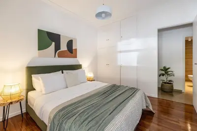 a bedroom with a large bed with white walls at Stylish 1BR Retreat Near Alimos Beach Tram in Athens