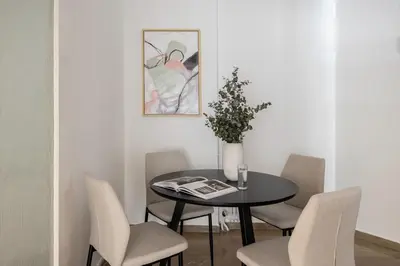 a dining room table with chairs and a vase with flowers at Stylish 1BR Retreat Near Alimos Beach Tram in Athens
