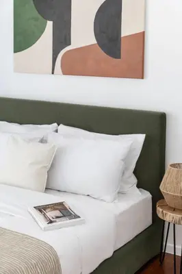 a bed with white pillows and paintings above it at Stylish 1BR Retreat Near Alimos Beach Tram in Athens
