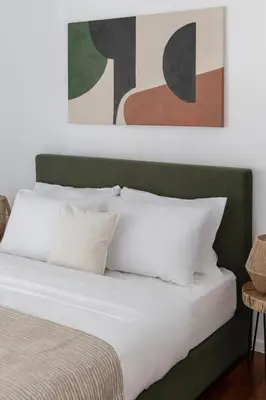 a bed with white pillows and paintings on the wall at Stylish 1BR Retreat Near Alimos Beach Tram in Athens