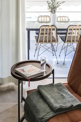 a coffee table with a book on it next to a table with chairs at Stylish 1BR Retreat Near Alimos Beach Tram in Athens