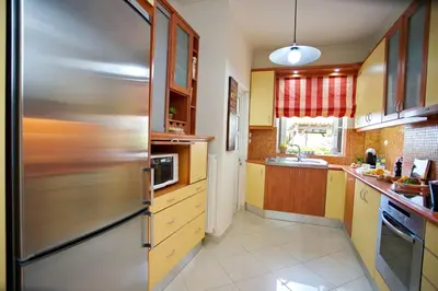 a kitchen with a stainless steel refrigerator and wooden cabinets at Blue Oliva House in Aghia Marina