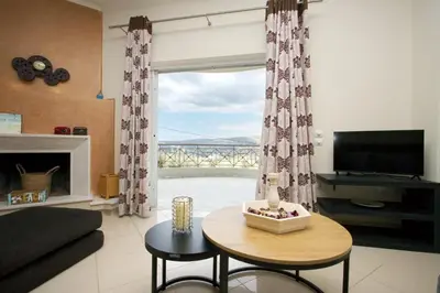 a living room with a table and a large window at Blue Oliva House in Aghia Marina