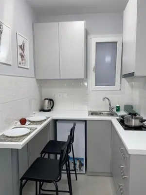 a white kitchen with two chairs and a sink at City Core Studio in Athens