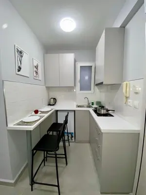 a white kitchen with a black chair and a table at City Core Studio in Athens