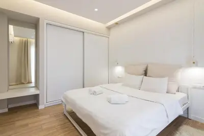a white bedroom with a large white bed with white pillows at Unique Apartment Ideal for Couples in Piraeus
