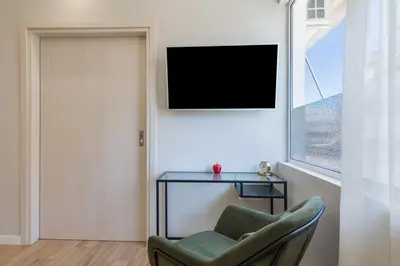 a living room with a chair and a tv on a wall at Unique Apartment Ideal for Couples in Piraeus