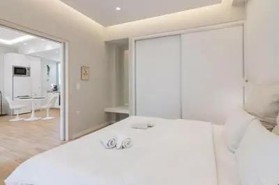 a white bedroom with a white bed and a dining room at Unique Apartment Ideal for Couples in Piraeus