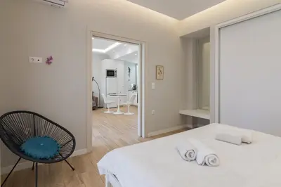 a bedroom with a white bed and a chair at Unique Apartment Ideal for Couples in Piraeus