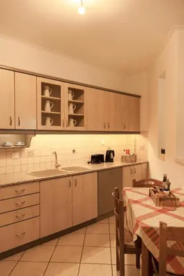 a kitchen with wooden cabinets and a table with a tableablish at Manolia house near beach in Aghia Marina