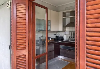 a kitchen with wooden cabinets and a glass door at aθens flat in Athens