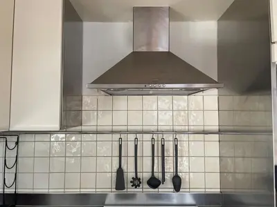 a kitchen with a stove with a hood and utensils at aθens flat in Athens