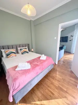 a bedroom with a large bed with a pink blanket at MediTerra Stay Athens Riviera Seaview in Athens