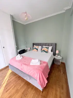 a bedroom with a large bed with a pink blanket at MediTerra Stay Athens Riviera Seaview in Athens
