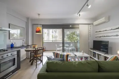 a living room with a green couch and a kitchen at Elegant Design Stay in Koukaki in Athens