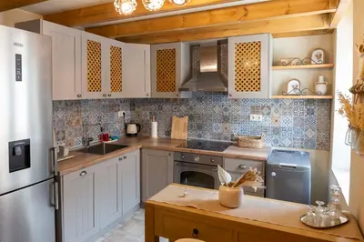 a kitchen with white cabinets and a stainless steel refrigerator at Strofilia House Near ATH Airport in Markopoulo