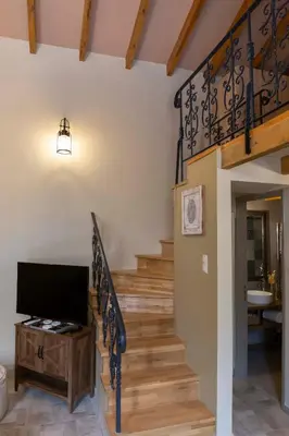 a living room with a staircase with a flat screen tv at Strofilia House Near ATH Airport in Markopoulo