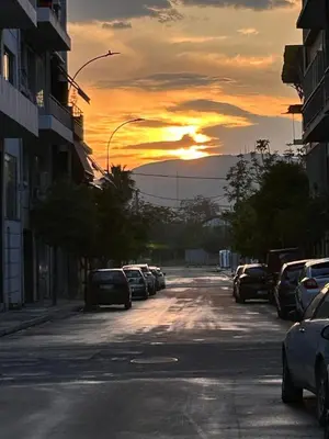 a street with cars parked on the street with the sun setting at Ben's Penthouse Athens in Athens