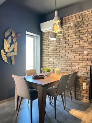 a dining room table with chairs and a brick wall at Ben's Penthouse Athens in Athens