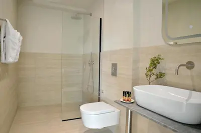 a bathroom with a shower and a toilet and a sink at The Apartment by Athenaeum Hotels in Athens