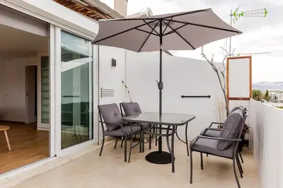 a table and chairs with an umbrella on a patio at Delimare, Acropolis & Sea View Rooftop, Paleo Faliro in Athens