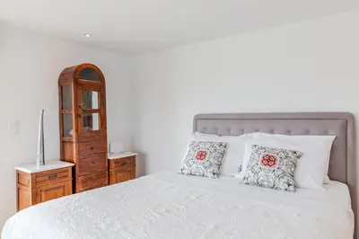 a bedroom with a white bed and a wooden dresser at Delimare, Acropolis & Sea View Rooftop, Paleo Faliro in Athens