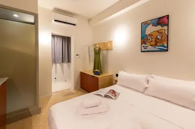 a bedroom with a white bed and a painting on the wall at Mooeve Psyri Studios in Athens