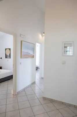 a white room with a bed and paintings on the wall at Aethra Villa in Sounio