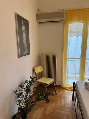 a room with a chair and a plant next to a window at Timeless Thissio Home in Athens