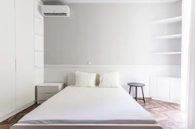 a white bedroom with a bed and a stool at Fully Renovated 2bdrm Apartment in Kolonaki area in Athens